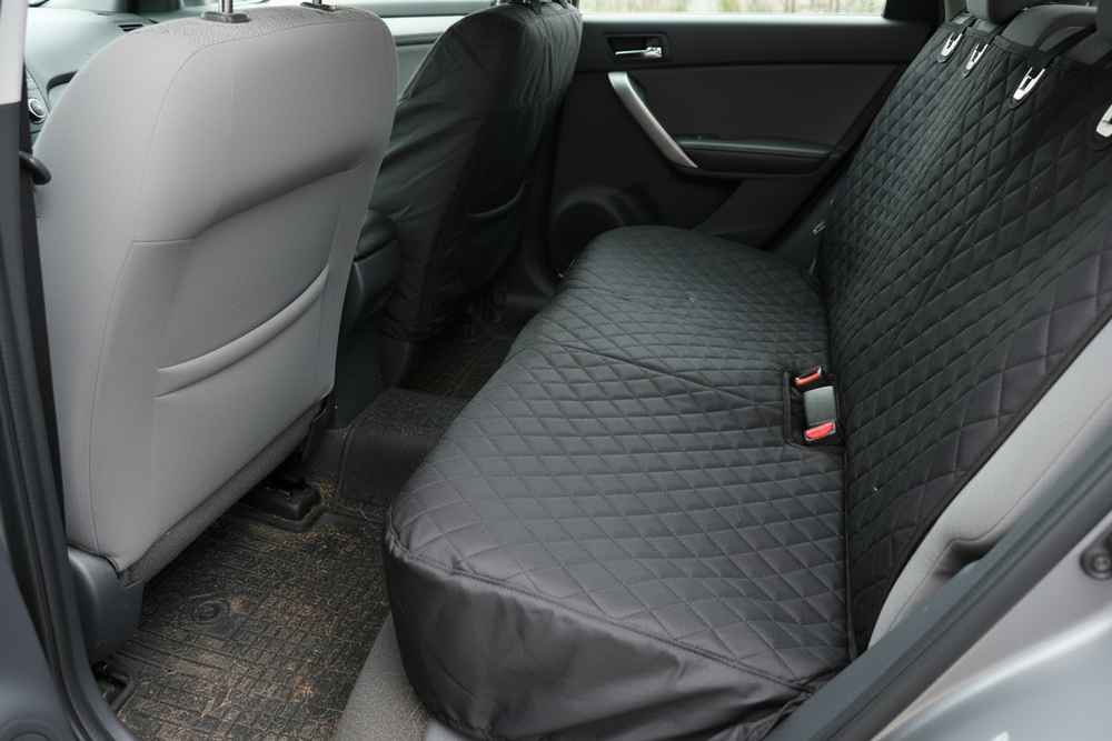 Quilted black seat cover installed on light grey seats
